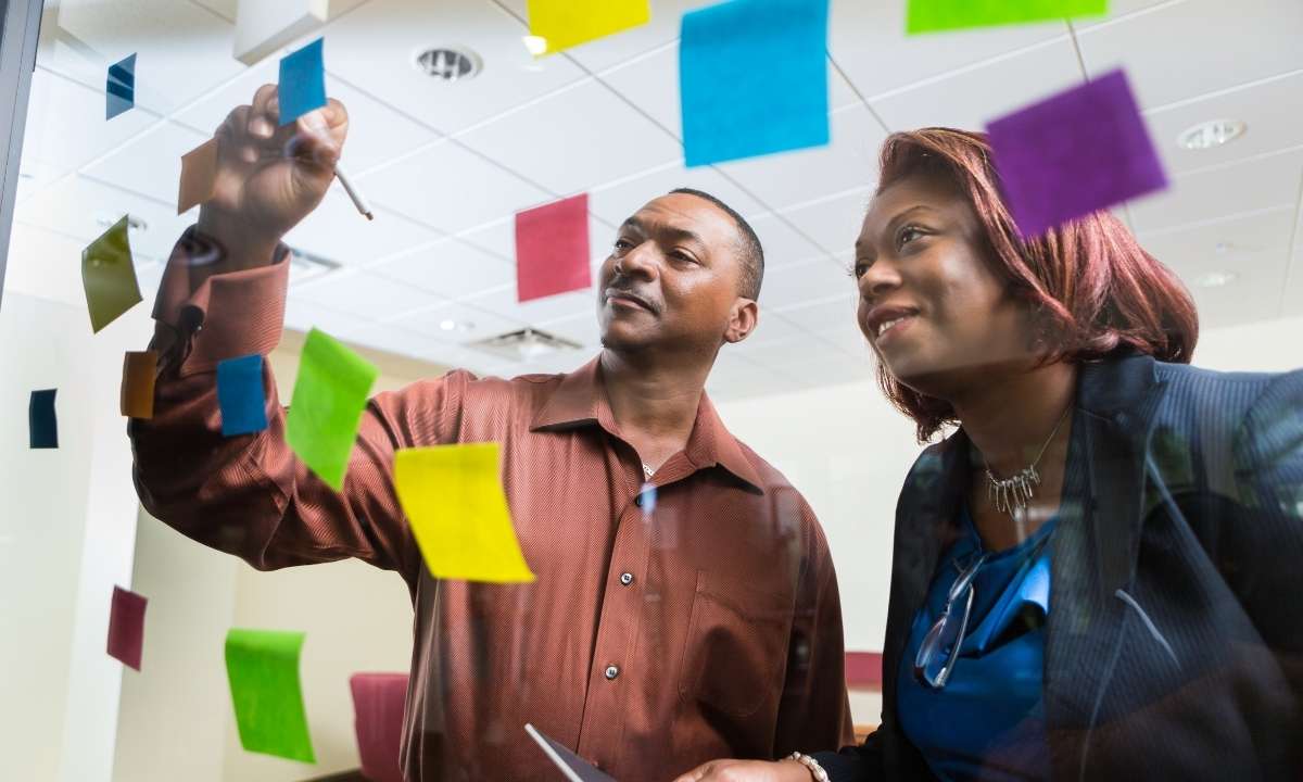 Duas pessoas planejando estratégia com post-its