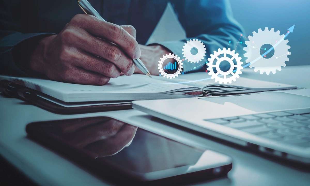 Mão escrevendo em caderno com engrenagens digitais